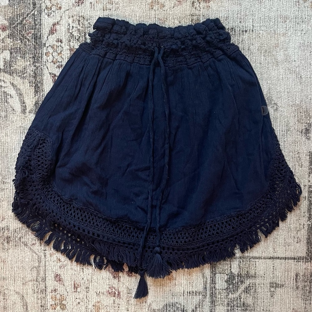 Navy blue linen skirt with tassel detailing and elastic waistband.